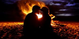 couple s'assoit devant un feu sur la plage