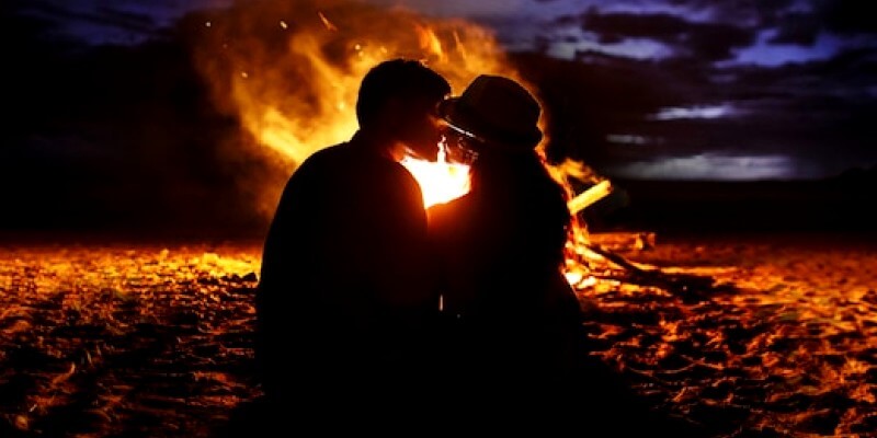 couple s'assoit devant un feu sur la plage